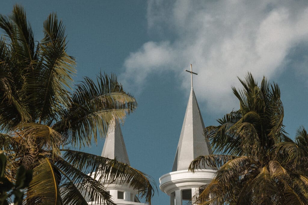 Two Church spires adorned with crosses between pam trees on Rote Island