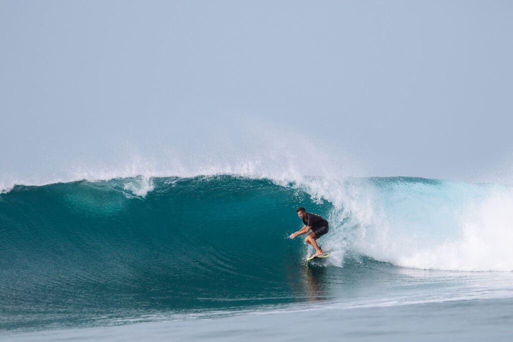 Surfer wearing a black shirt rides the tropical blue water wave of Boa