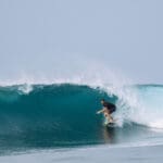 Surfer wearing a black shirt rides the tropical blue water wave of Boa